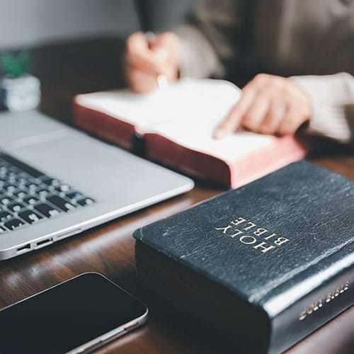 The Holy Bible, a laptop, and a smartphone